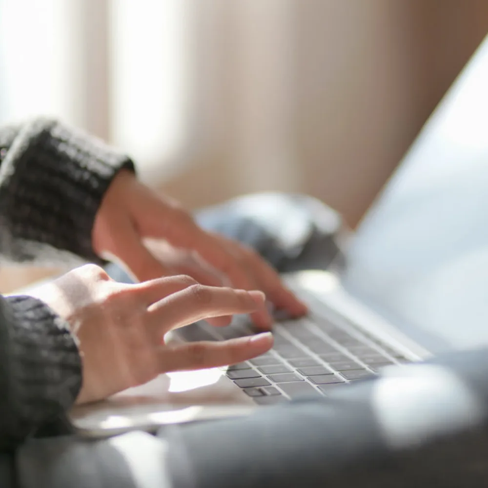 Handen op een laptop, zacht daglicht op de achtergrond. Consult per e-mail, Leven op gevoel.
