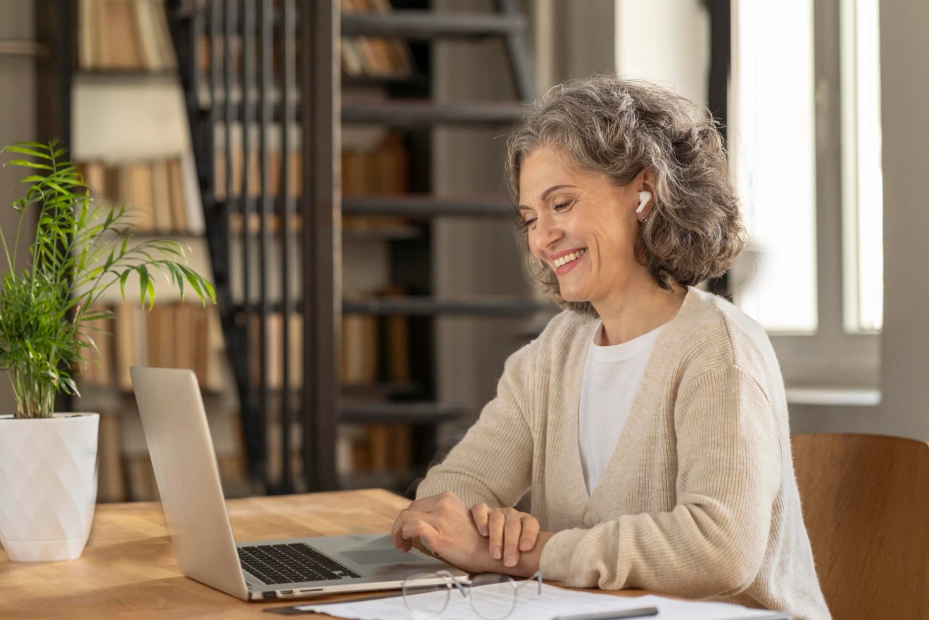 Vrouw neemt glimlachend deel aan de online groepscursus van Leven op gevoel via Zoom